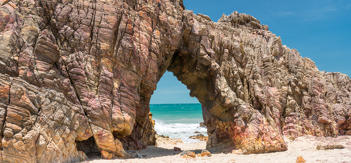 Foto de uma formação chamada "pedra furada", na praia de Jericoacoara, de uma rocha com um furo no meio