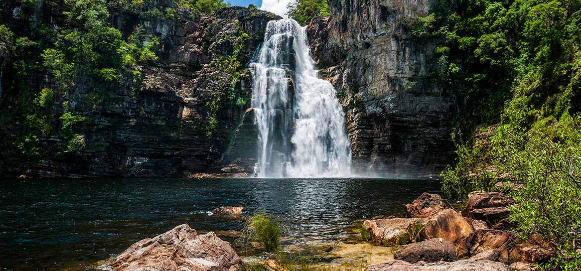 Foto de uma cachoeira da Chapada dos Veadeiros (GO) cercada de rochas e vegetação.