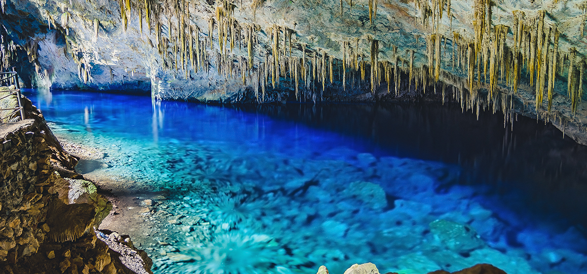 Foto do Lago Azul, em Bonito (MS), com vista da água azul transparente e formação de estalactites no teto da gruta.
