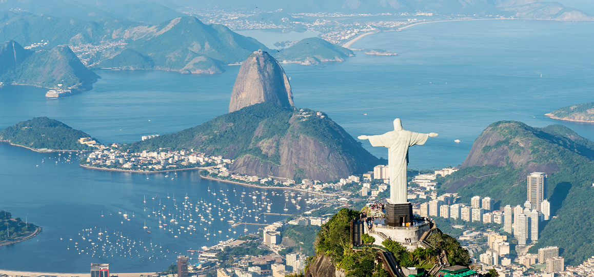 Foto aérea da paisagem do Rio de Janeiro: a estátua do Cristo Redentor, a baía e, ao fundo, o Pão de Açúcar