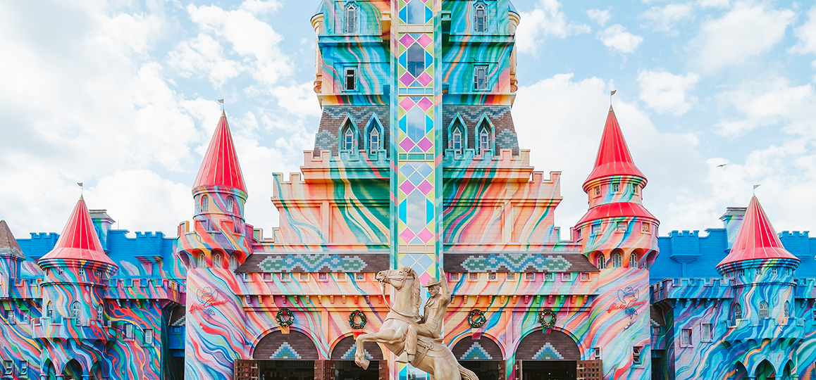 Foto do parque Beto Carrero World: à frente, está uma estátua de seu fundador montado em um cavalo; ao fundo, um castelo colorido