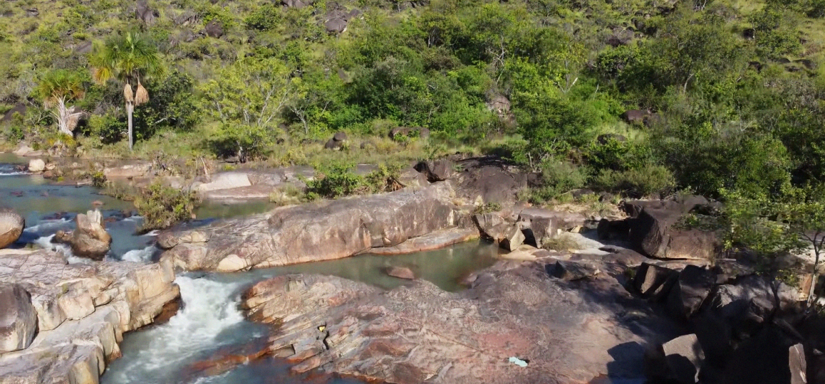 Foto com vista vista aérea da Cachoeira da Raposa, em Roraima, com vegetação abundante ao fundo.